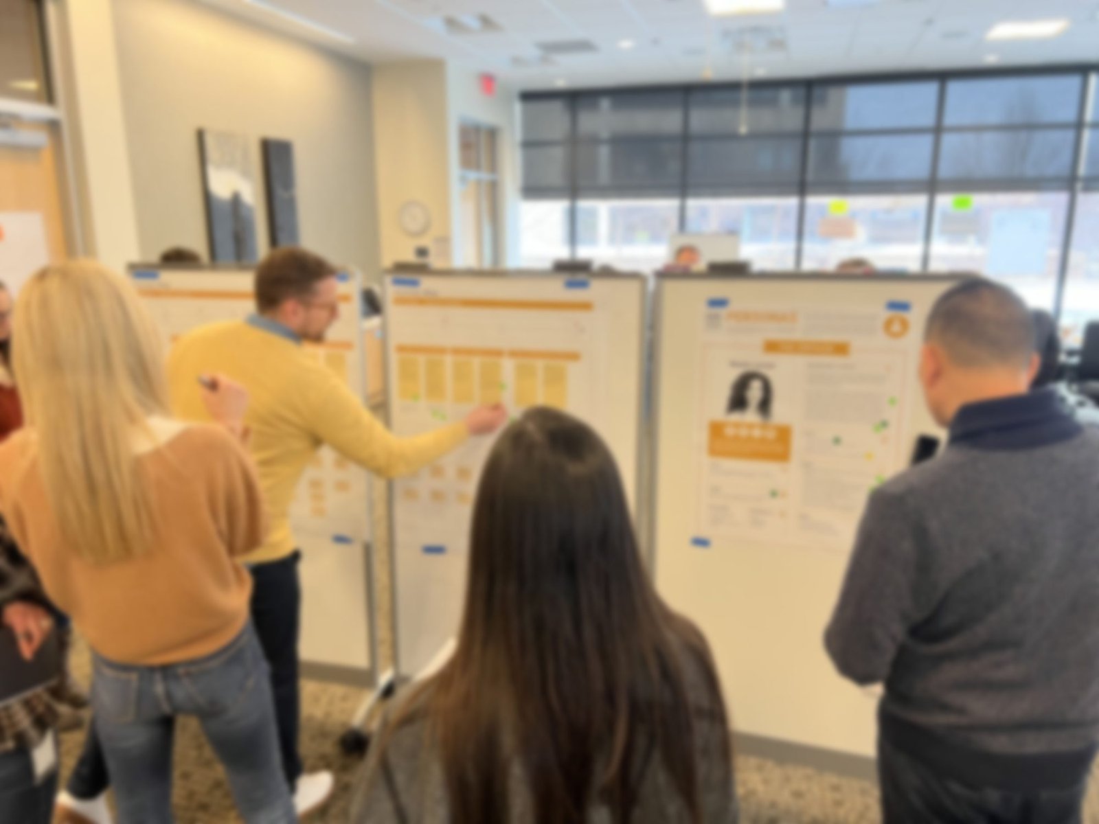 Colleagues reviewing printed persona and journey map research boards during a workshop.